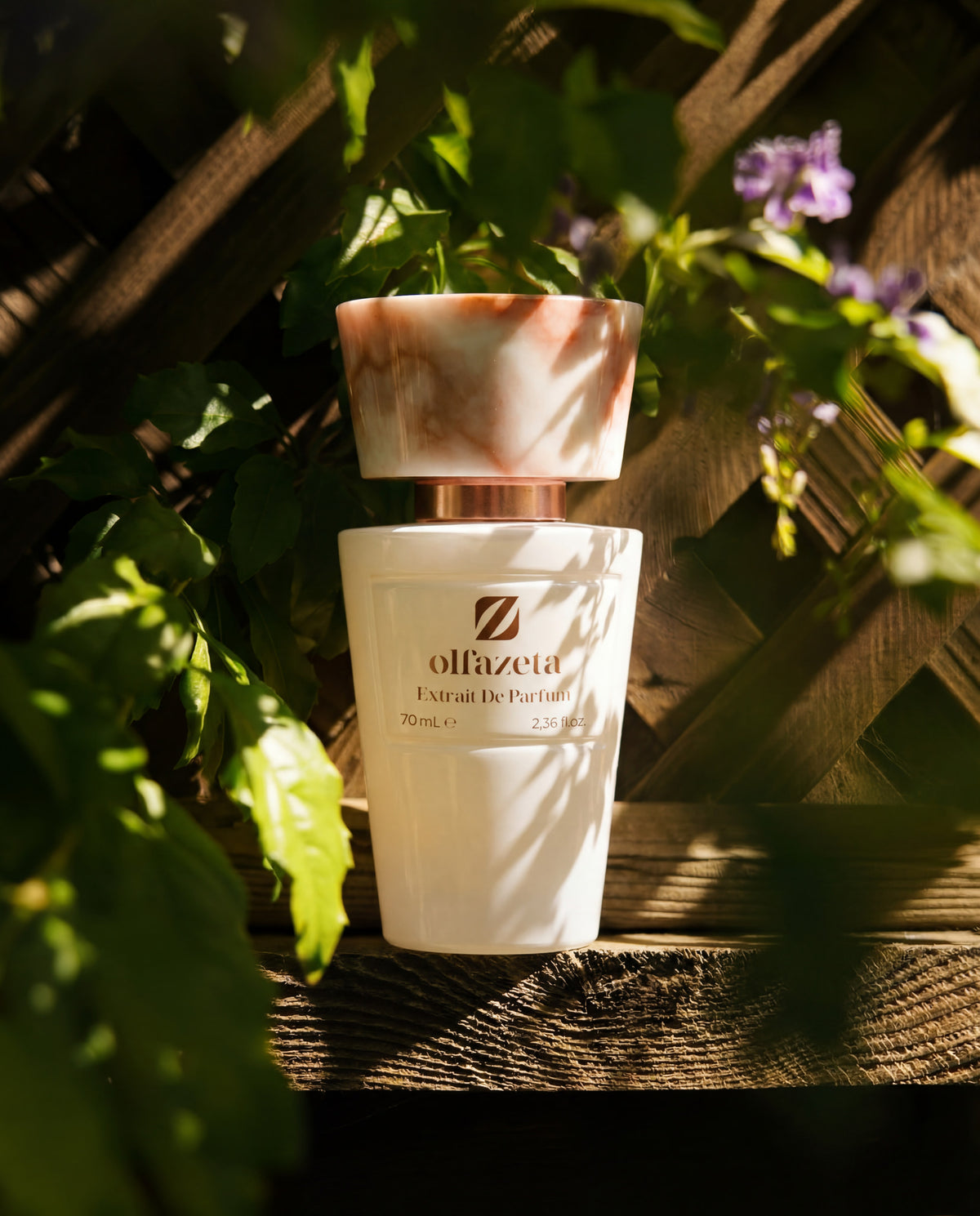 Balts flakons Olfazeta by Chogan Millésime N°53 uz koka rešģa, zaļas lapas un gaiši violeti ziedi